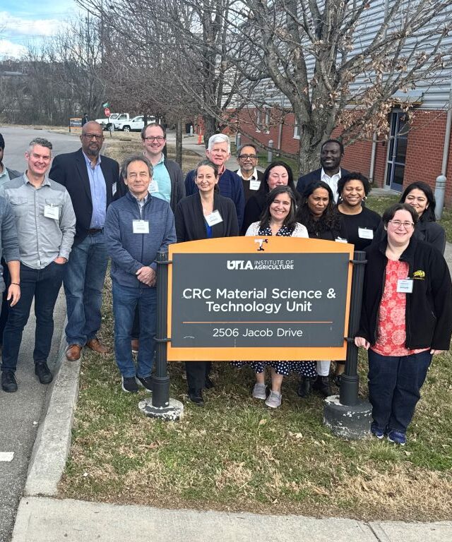 Team members standing beside the Center for Renewable Carbon sign. 
